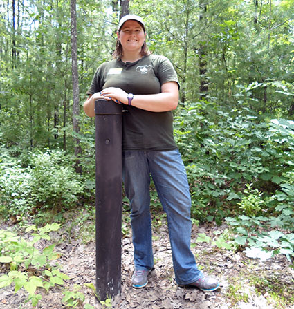A Green Circle Trail intern stands next to an infrared trail counter.